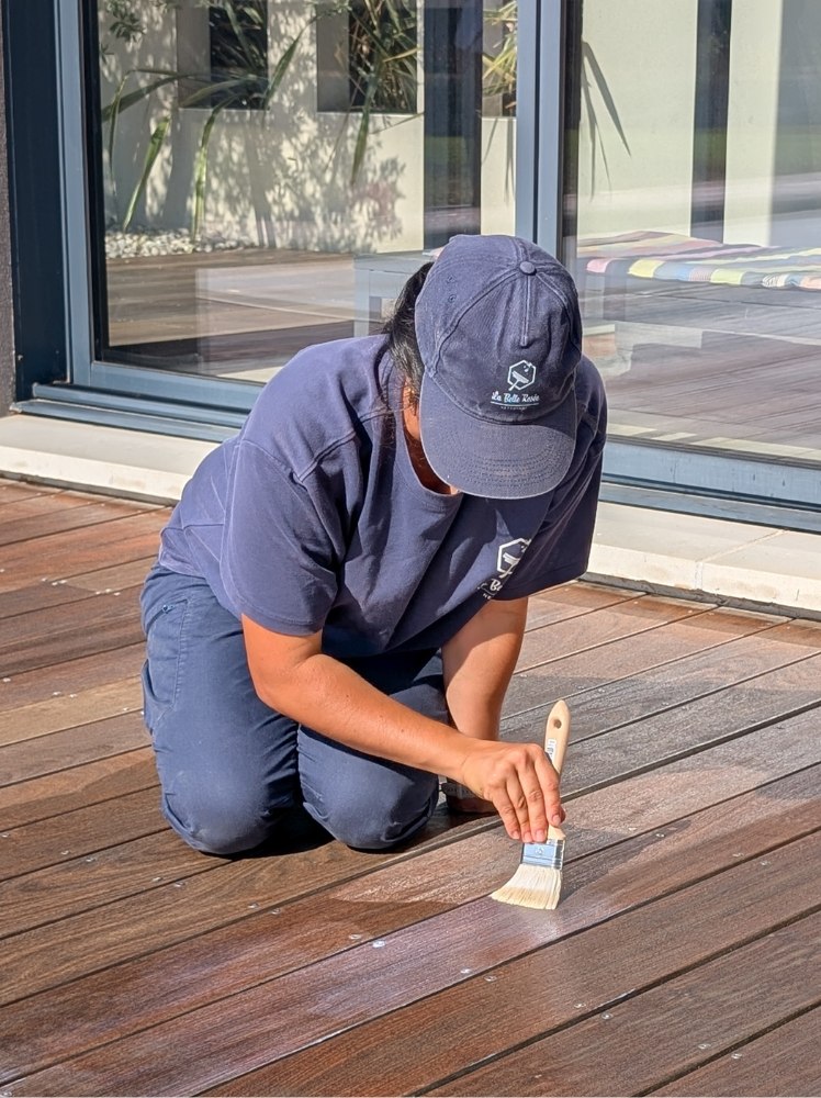 Tatiana appliquant le saturateur au pinceau sur une terrasse en bois