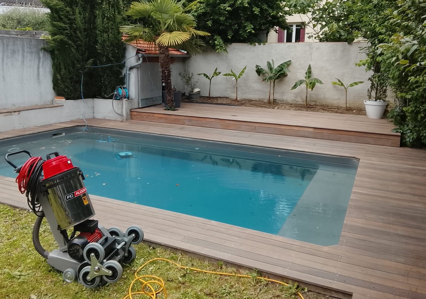 Machine de nettoyage à sec au bord d'une terrasse bois de piscine
